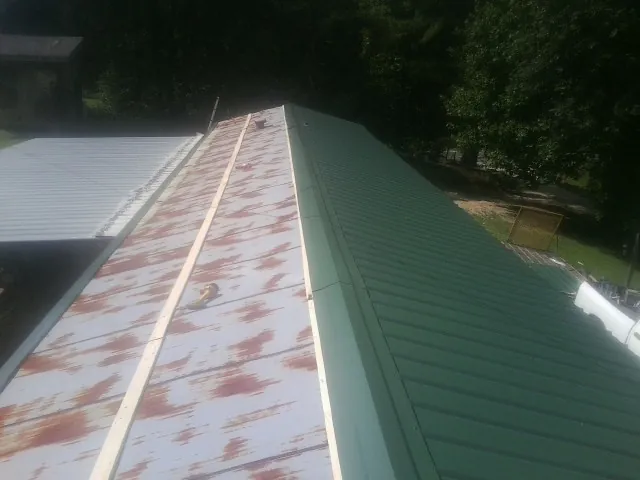 Old rusted panels beside newly installed green metal roofing — Wind Damage Roof Repair by Roofing Brothers in Apopka