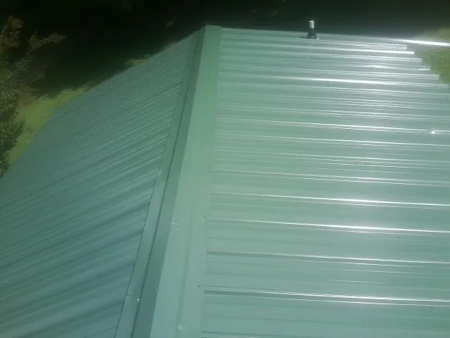 New green metal panels meeting at the ridge of a roof — Flat Roof Repair work by our crew in Apopka