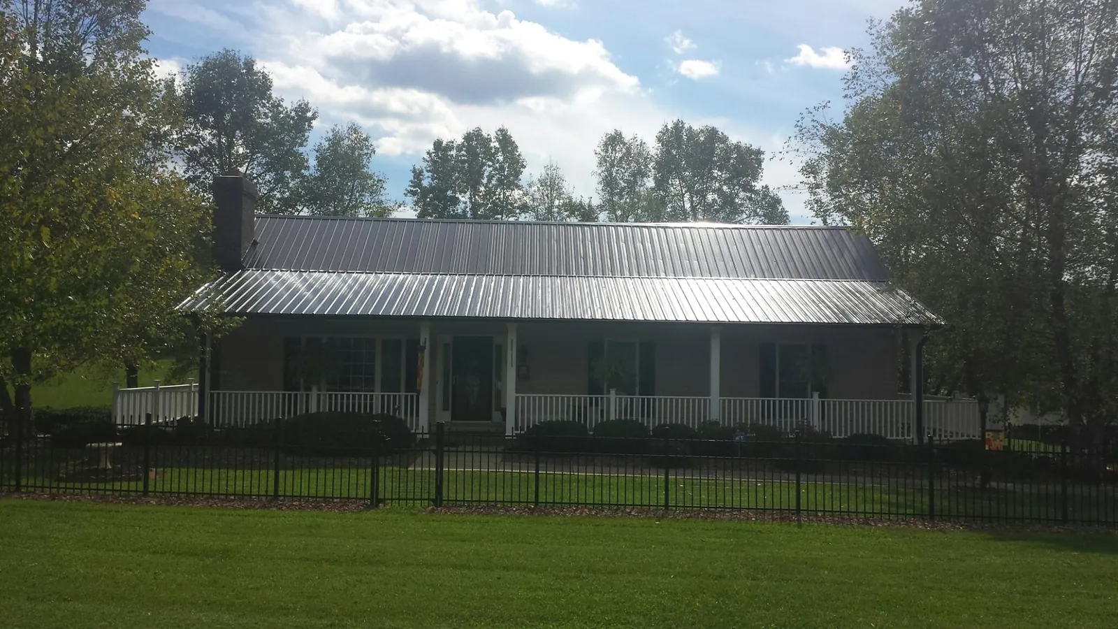 Gray metal roof on a brick ranch with a full width front porch — Gutter Guard Installation work by our crew in Apopka