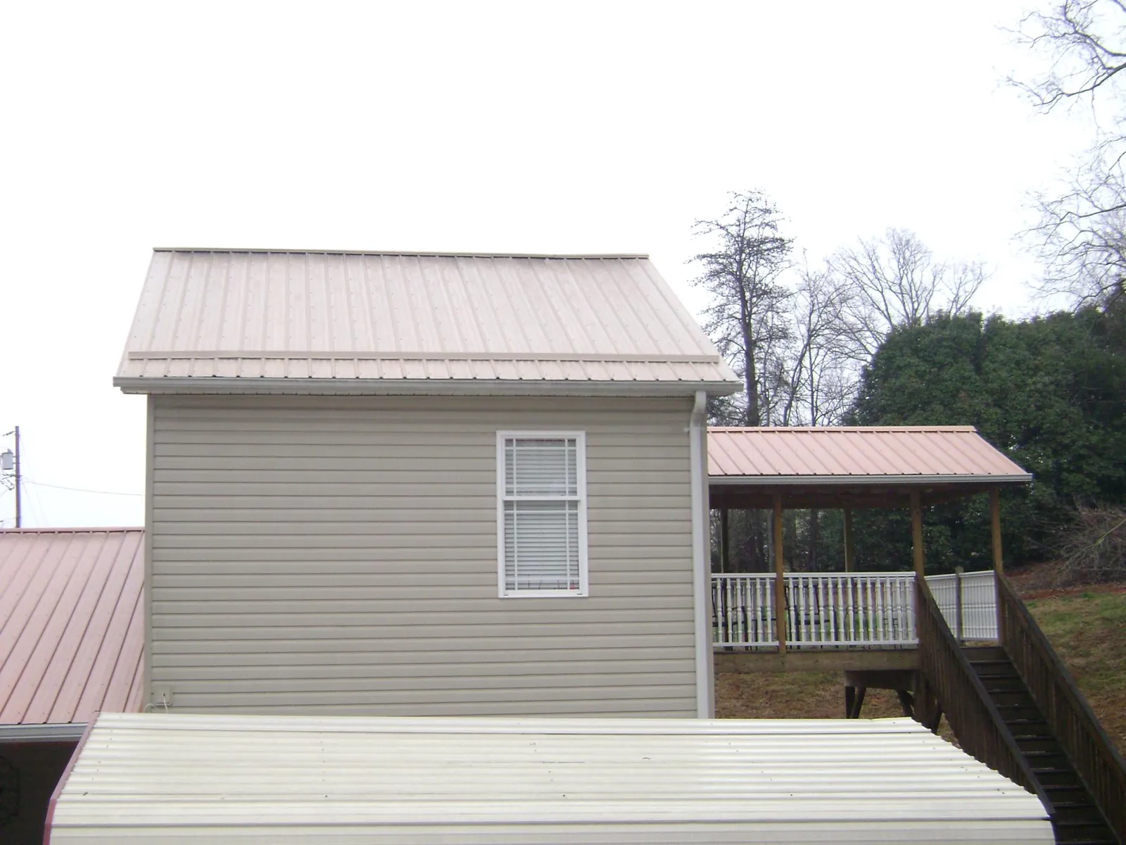 Tan metal roofs on a two story addition and attached porch, from a Roof Replacement job in Apopka